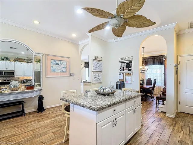 Kitchen with light hardwood / wood-style floors, white cabinets, stainless steel appliances, a center island, and ceiling fan