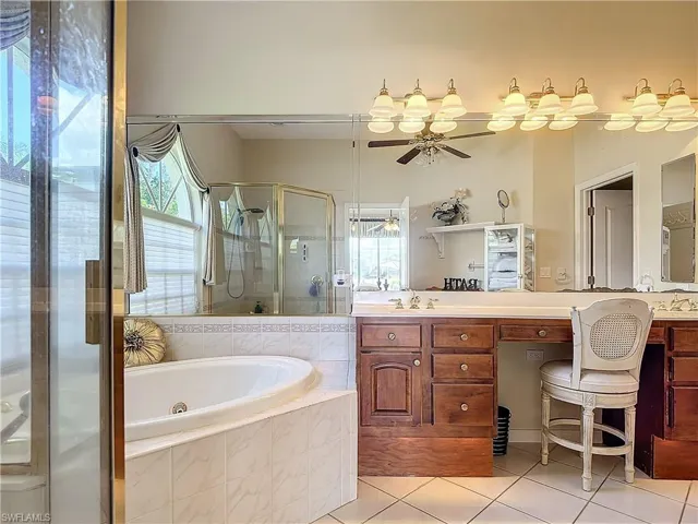 Bathroom with tile patterned floors, ceiling fan, independent shower and bath, and vanity