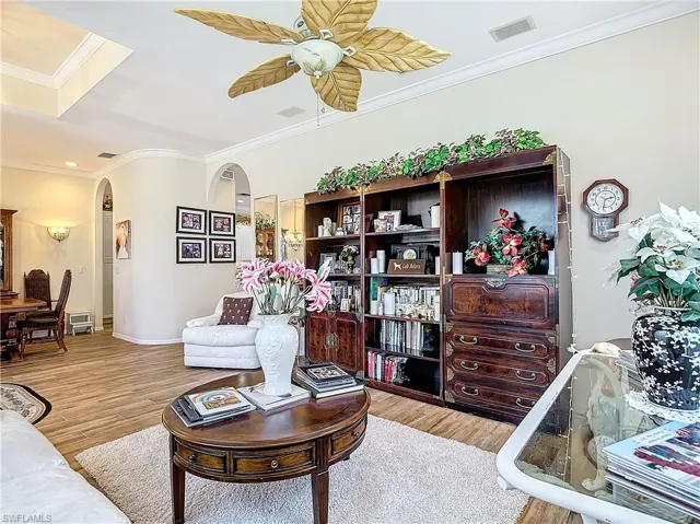 Living room featuring ceiling fan, hardwood / wood-style flooring, and crown molding