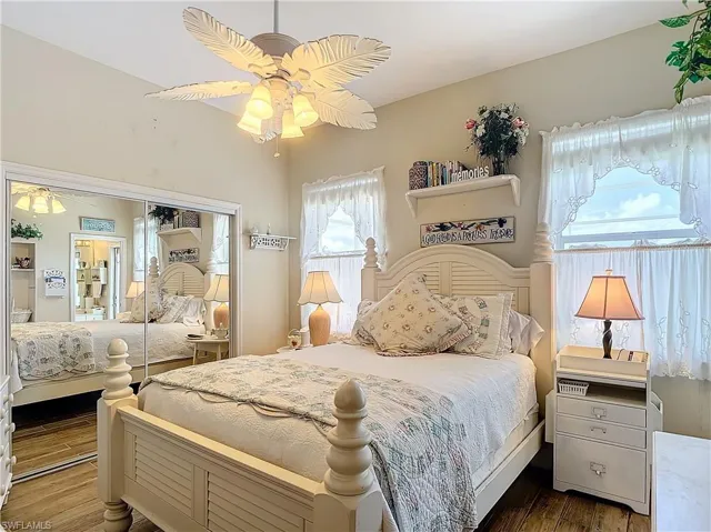 Bedroom with dark hardwood / wood-style flooring, ceiling fan, and a closet