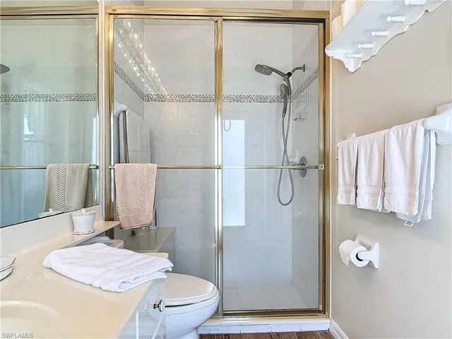 Bathroom featuring sink, a shower with shower door, and toilet