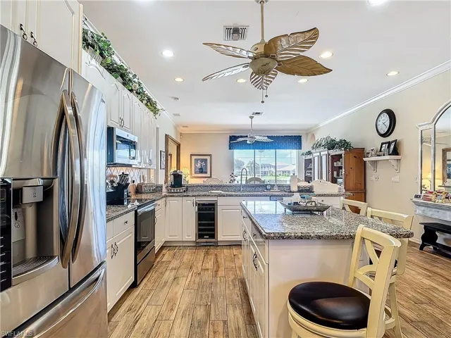 Kitchen featuring wine cooler, light hardwood / wood-style floors, a kitchen breakfast bar, stainless steel appliances, and ceiling fan