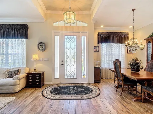 Foyer featuring an inviting chandelier, crown molding, and hardwood / wood-style floors