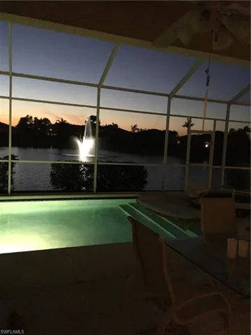 Pool at dusk featuring a water view
