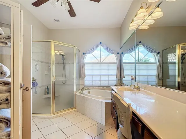 Bathroom with ceiling fan, separate shower and tub, vanity, and tile patterned flooring