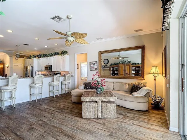 Living room with wood-type flooring, crown molding, and ceiling fan