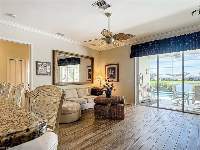 Living room featuring ceiling fan, crown molding, wood-type flooring, and a wealth of natural light