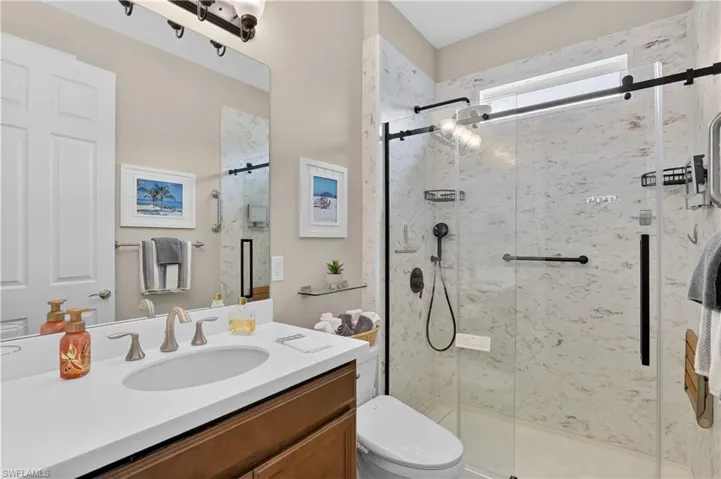 Bathroom with vanity and a marble finish shower