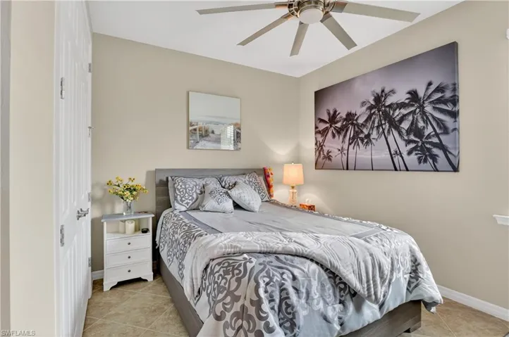Bedroom with ceiling fan, light tile patterned floors, and a closet