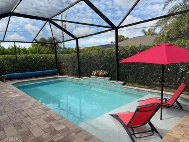 View of swimming pool featuring screen enclosure, a covered pool, a sundeck, for lounging poolside.
