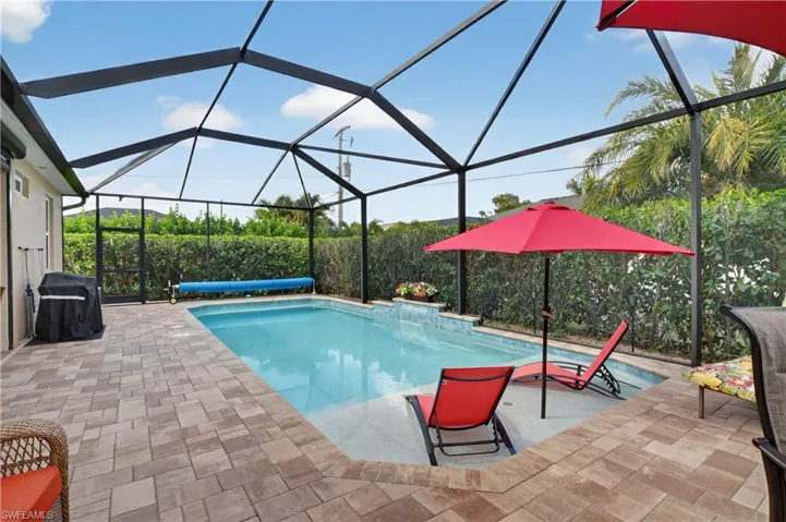 Swimming pool with a sunroom, glass enclosure, and area for grilling