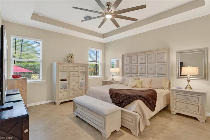 Bedroom with a tray ceiling, ceiling fan, and light tile patterned flooring