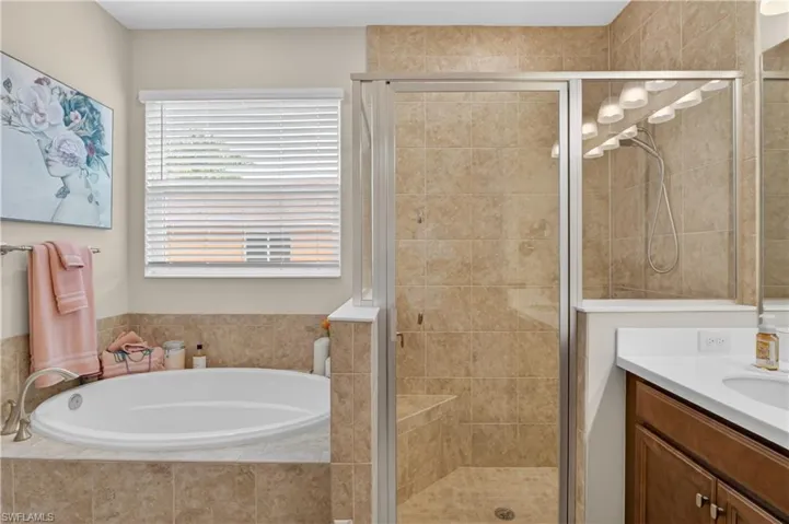 Bathroom with a stall shower, a bath, and vanity