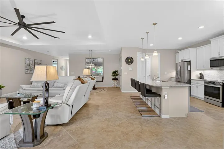 Living room featuring a ceiling fan, recessed lighting, light tile patterned flooring, and a raised ceiling