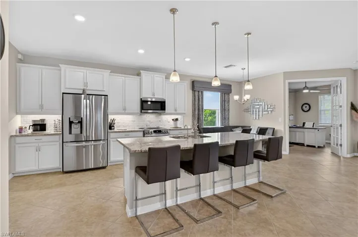 Kitchen with stainless steel appliances, light stone counters, a breakfast bar, and white cabinets