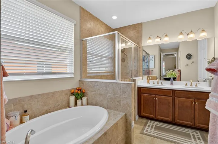 Bathroom with double vanity, a garden tub, and a stall shower