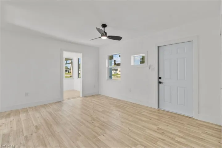 Wood-finish flooring, white walls, black ceiling fan, and white window frames