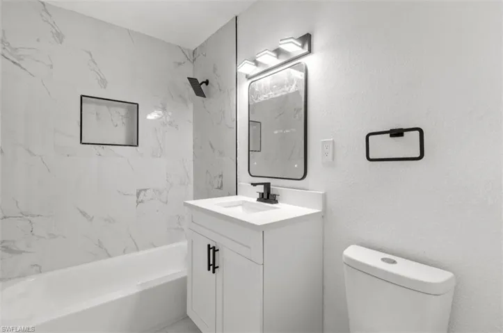 White vanity with a single sink, quartz countertop, and black faucet
