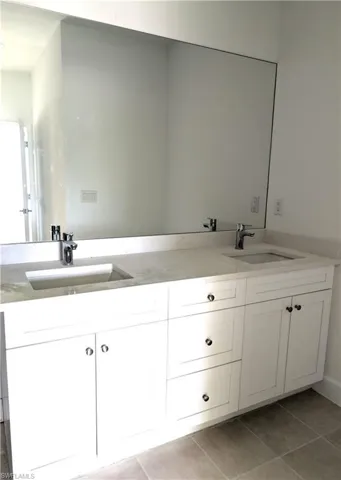 Full bath featuring double vanity and light tile patterned flooring