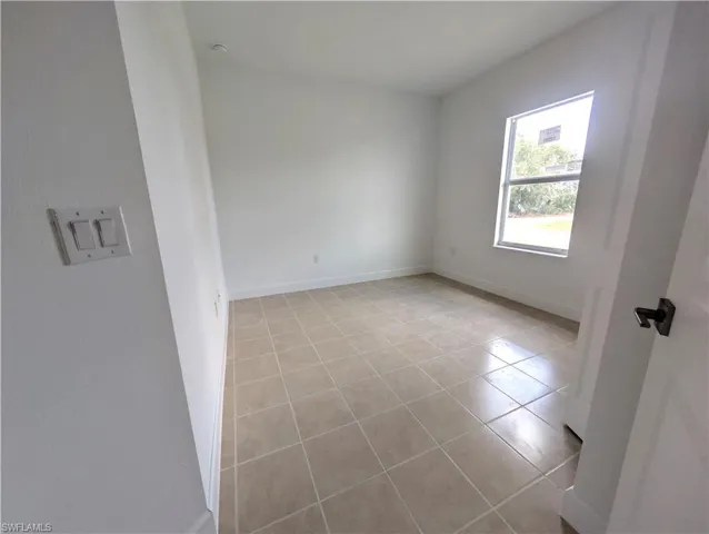Empty room featuring light tile patterned floors and baseboards