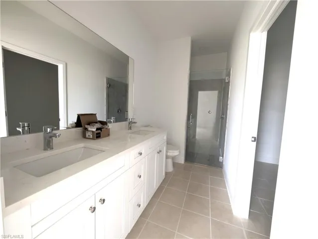 Full bathroom with a stall shower, light tile patterned flooring, and double vanity