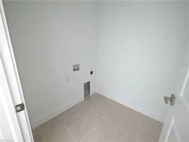 Washroom with light tile patterned floors, washer hookup, and hookup for an electric dryer