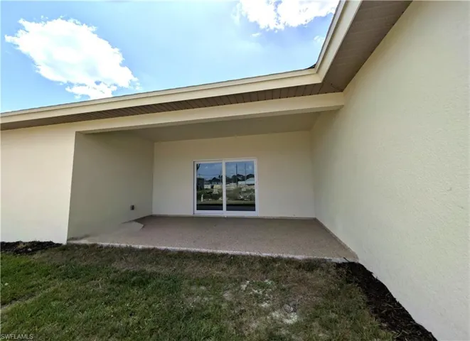Back of house featuring stucco siding, a patio area, and a lawn