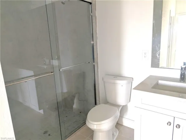 Bathroom with vanity, light tile patterned floors, and a stall shower