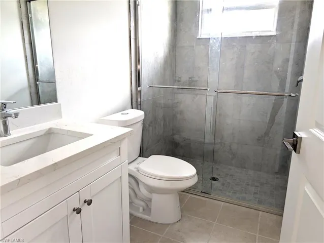 Bathroom with vanity, a shower stall, and light tile patterned floors