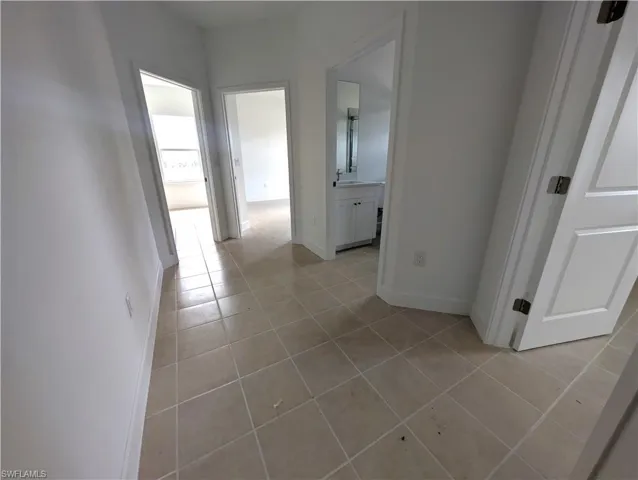 Corridor featuring light tile patterned floors and baseboards