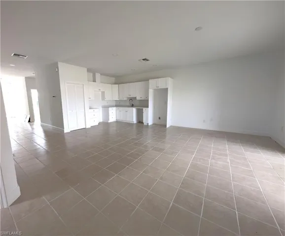 Unfurnished living room featuring light tile patterned floors and baseboards