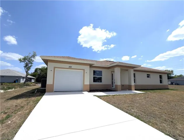 Prairie-style home featuring stucco siding, concrete driveway, an attached garage, and a front yard