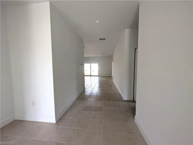 Corridor featuring light tile patterned flooring and baseboards