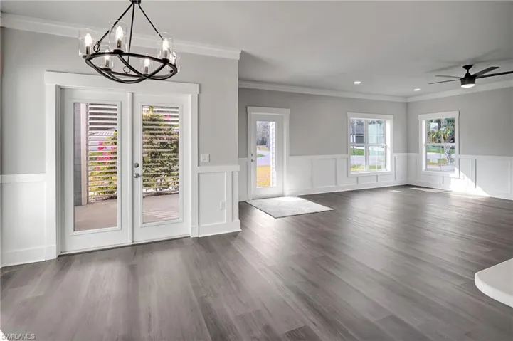 Unfurnished dining area featuring dark wood-type flooring, ceiling fan, ornamental molding, and french doors