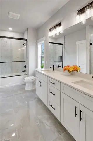 Full bathroom featuring vanity, combined bath / shower with glass door, and toilet