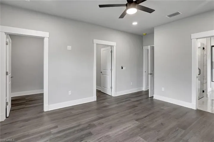 Unfurnished bedroom featuring dark wood-type flooring, ceiling fan, and connected bathroom
