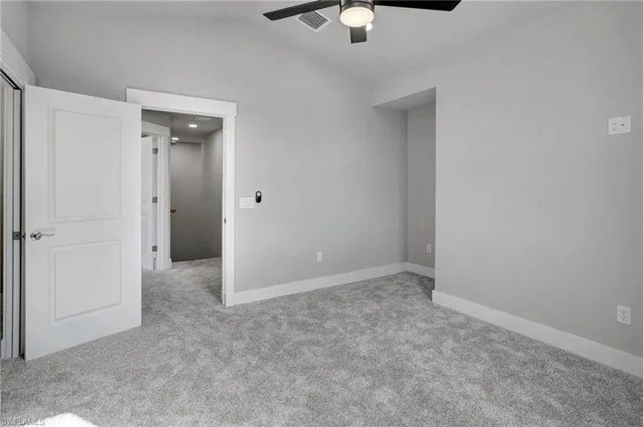Unfurnished bedroom featuring ceiling fan, lofted ceiling, and light carpet