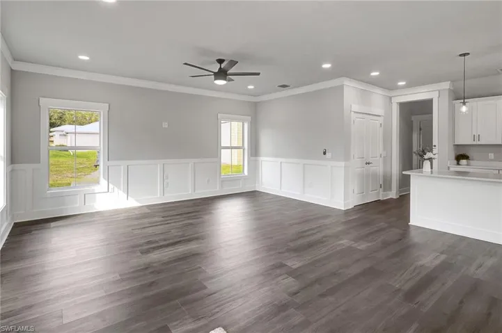 Unfurnished living room with ceiling fan, dark hardwood / wood-style flooring, and a wealth of natural light