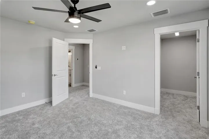 Unfurnished bedroom with ceiling fan and light colored carpet