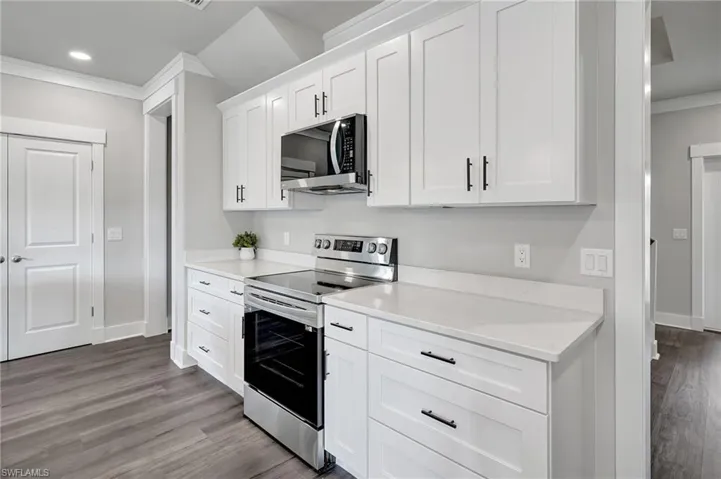 Kitchen featuring white cabinetry, crown molding, light hardwood / wood-style flooring, and appliances with stainless steel finishes