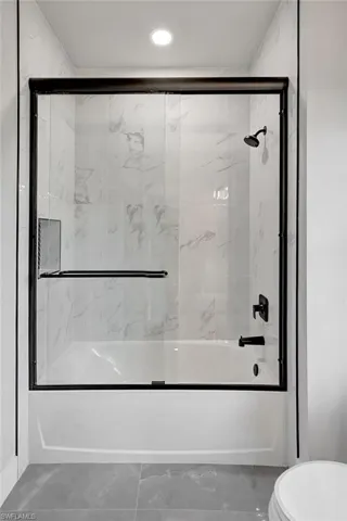 Bathroom featuring enclosed tub / shower combo and toilet