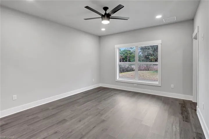 Empty room with dark hardwood / wood-style floors and ceiling fan