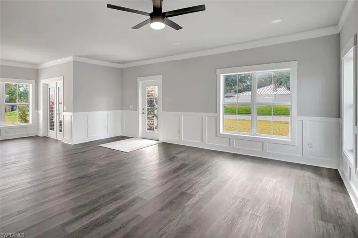 Unfurnished room featuring crown molding, a wealth of natural light, dark hardwood / wood-style floors, and ceiling fan