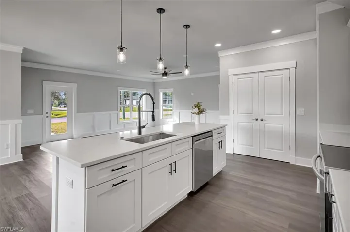 Kitchen featuring pendant lighting, an island with sink, sink, white cabinets, and stainless steel appliances