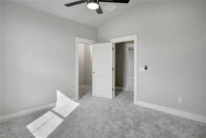 Unfurnished bedroom featuring vaulted ceiling, light carpet, and ceiling fan