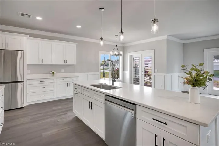 Kitchen with white cabinetry, sink, pendant lighting, and appliances with stainless steel finishes