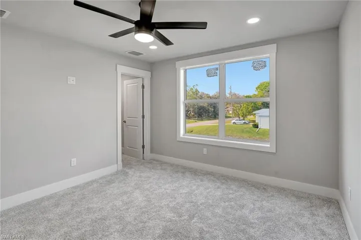 Empty room with ceiling fan and light colored carpet