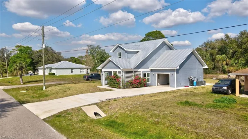 View of front facade featuring cooling unit, a garage, and a front lawn