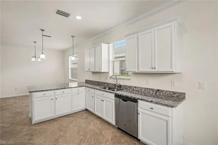 Kitchen featuring white cabinetry, stone countertops, stainless steel dishwasher, tile flooring, and pendant lighting