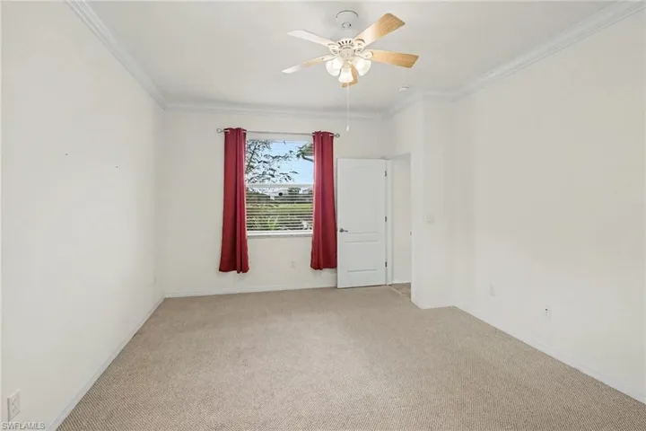 Recessed window with blinds, ceiling fan with light fixture, neutral carpeting, crown molding, and white interior door
